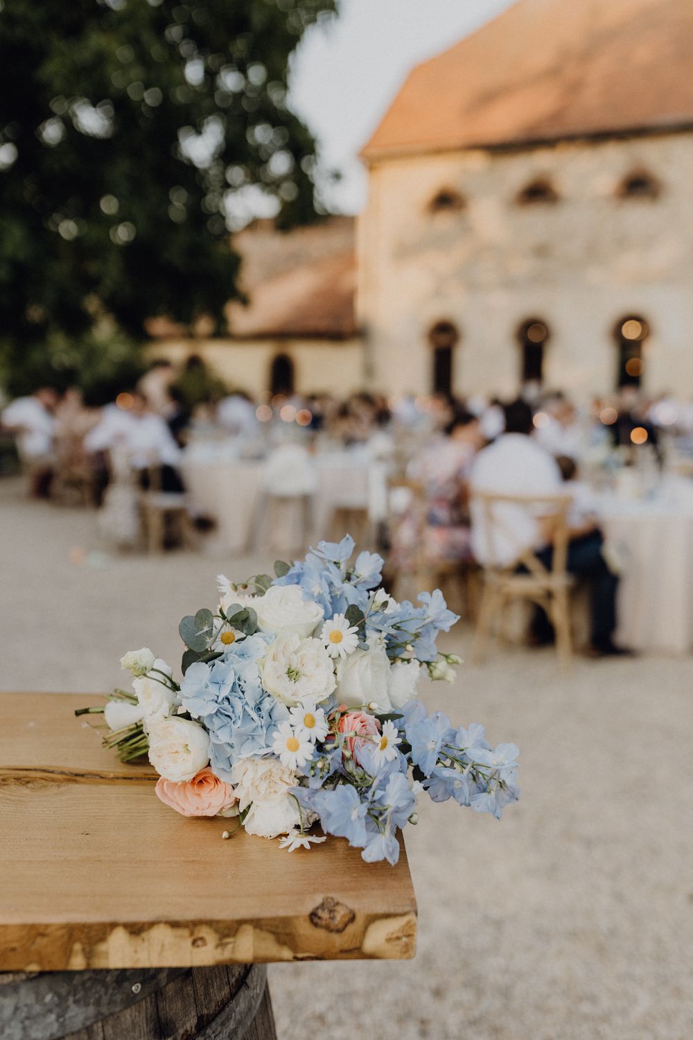 Abendstimmung bei einer Sommerhochzeit im Hofgut Heidesheim. Der Fokus liegt auf dem Brautstrauß, der auf einem Tisch liegt.