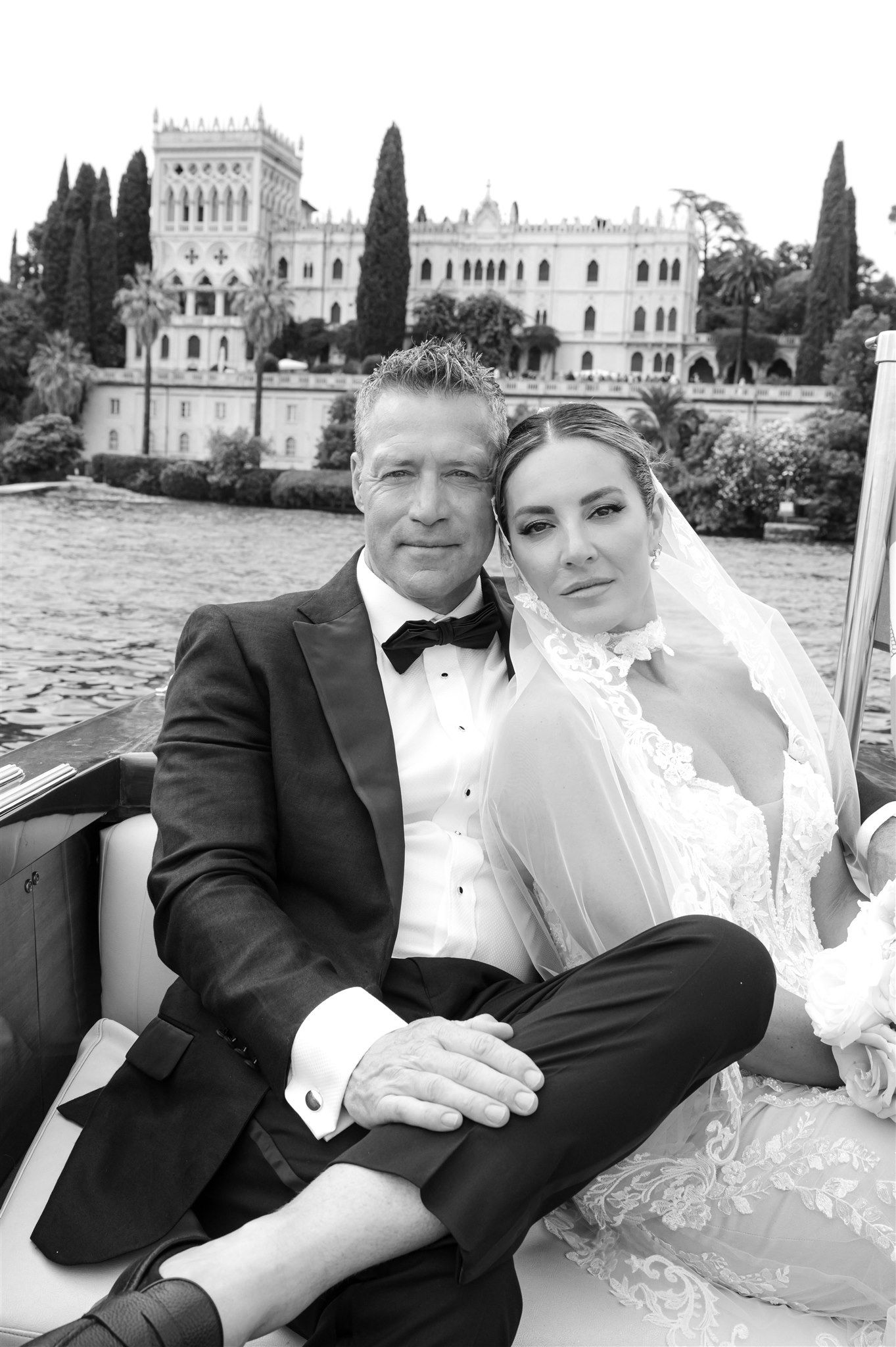 Newlyweds sharing intimate moments on a wooden boat with waterfront architecture in the background.