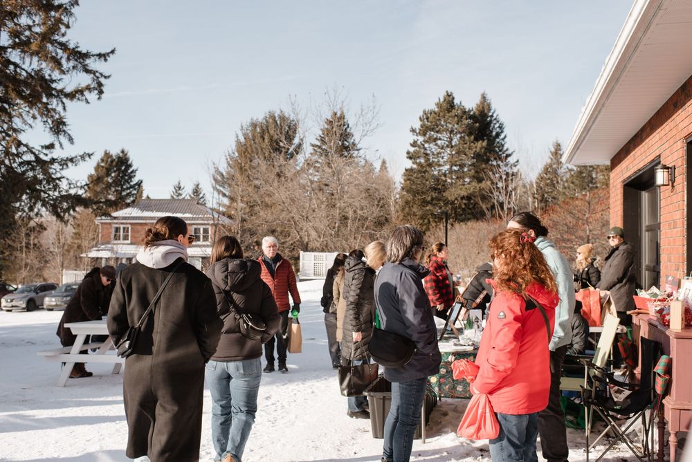 A winter snowy scene with people walking along a path in the snow on a cold day.