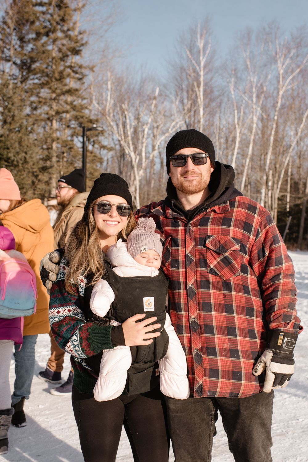 A group enjoys a winter day outdoors in the snow wearing red plaid flannel and warm winter gear.
