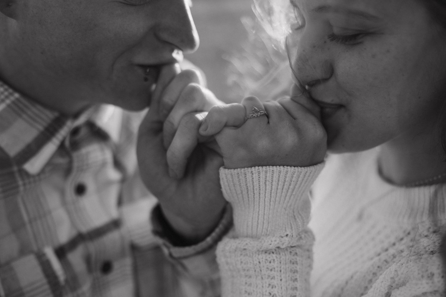 A black and white vintage photo shows two people sharing a cigarette in an intimate moment.