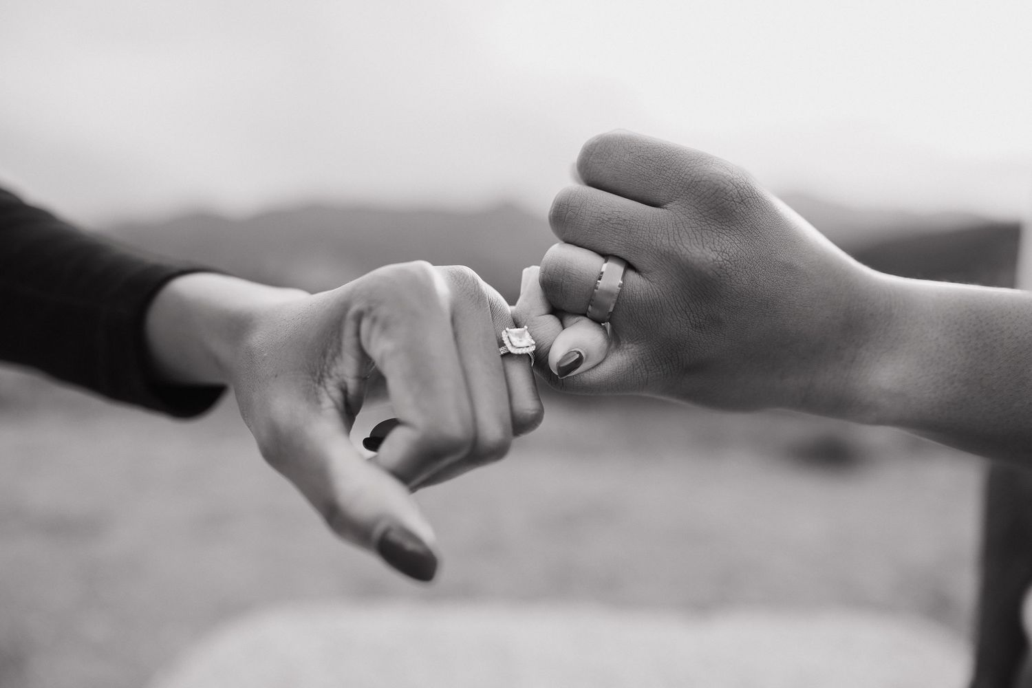 Black and white image showing a sequence of hands joining together in a supportive chain formation.