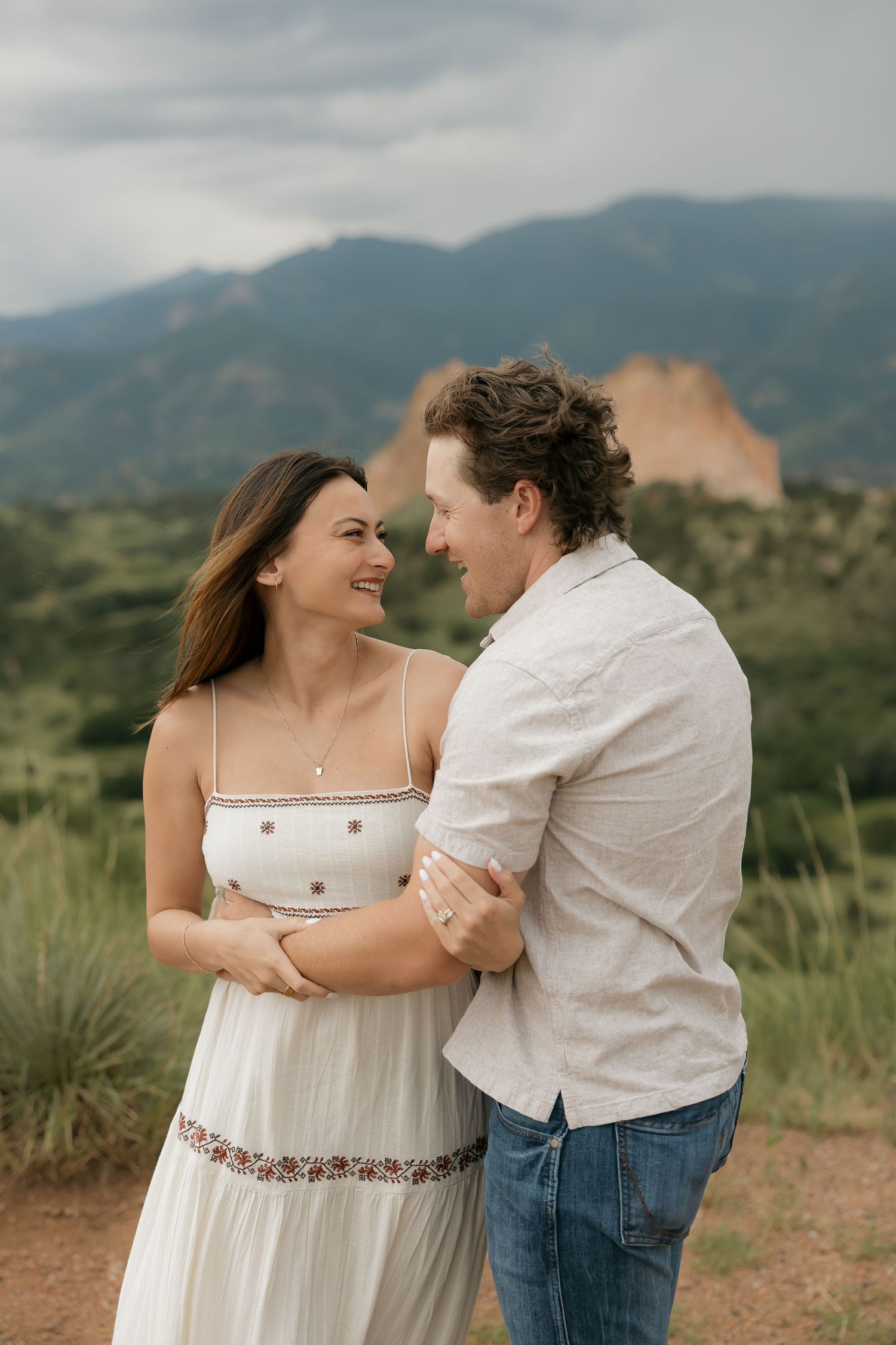 A romantic couple shares tender moments against a desert mountain landscape with desert plants and cacti in the background.