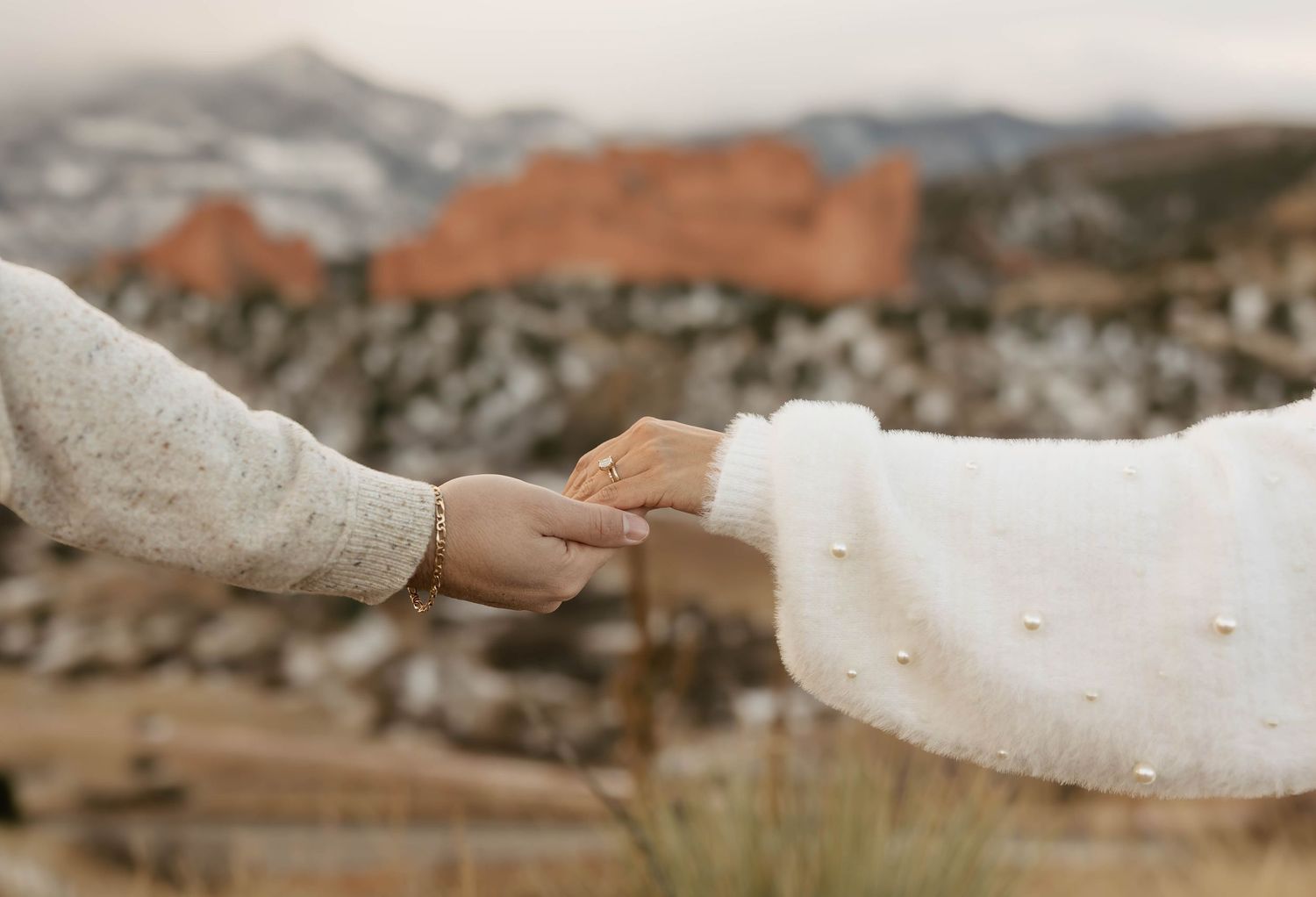A hand holding a piece of white bread dough while kneading and shaping it on a floured surface.