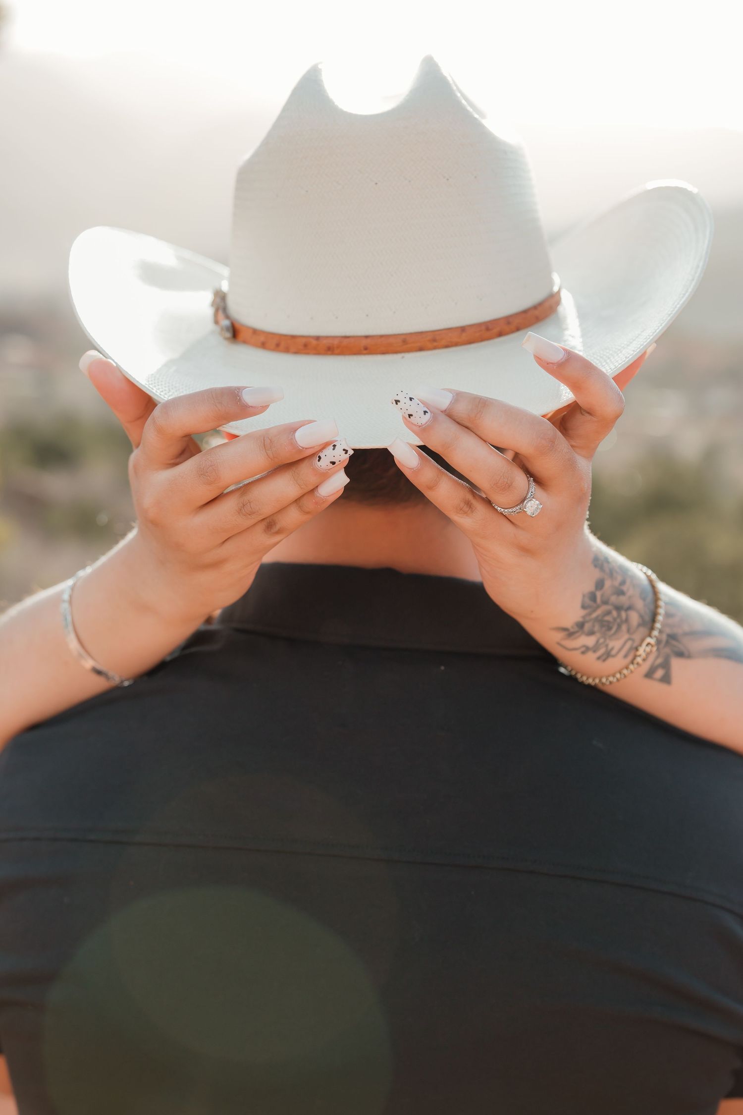 A hand with painted nails holds a white ceramic plate or dish with an orange rim against a black surface.