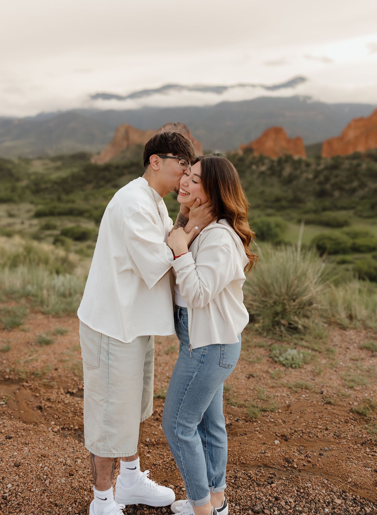 Couple in white outfits sharing tender moments against the backdrop of Garden of the Gods in Colorado.