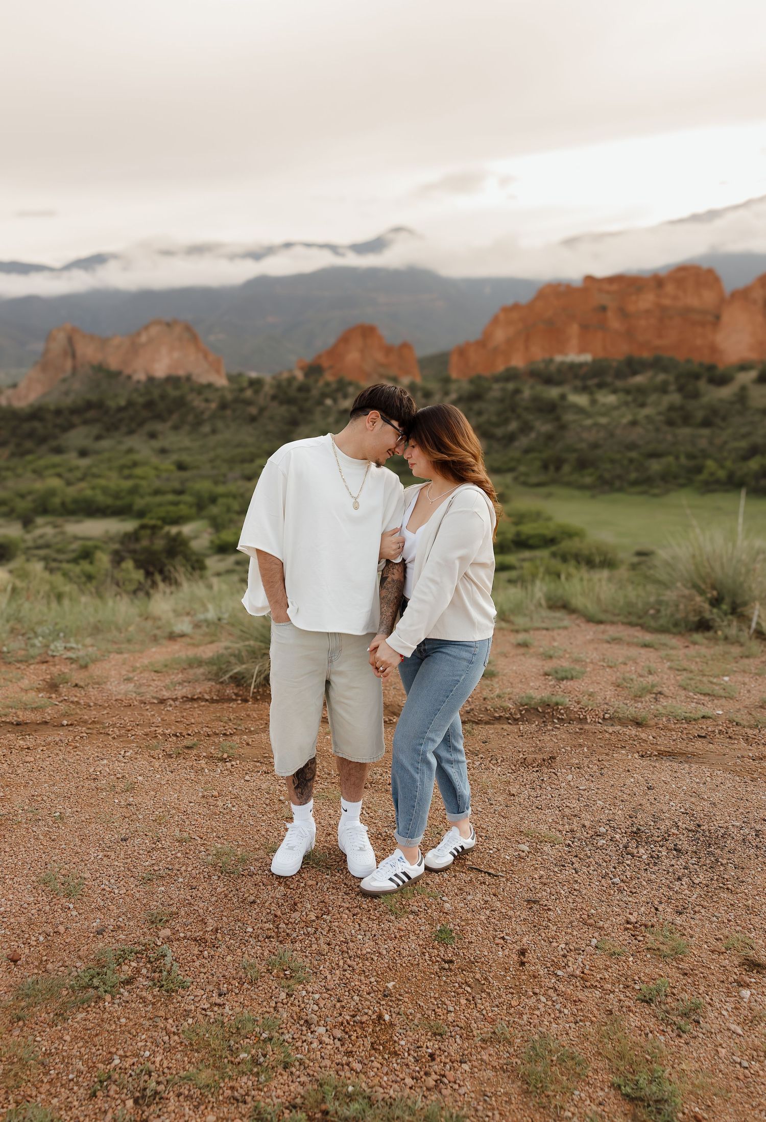 A couple shares an intimate moment at Garden of the Gods in Colorado Springs with red rock formations in the background.