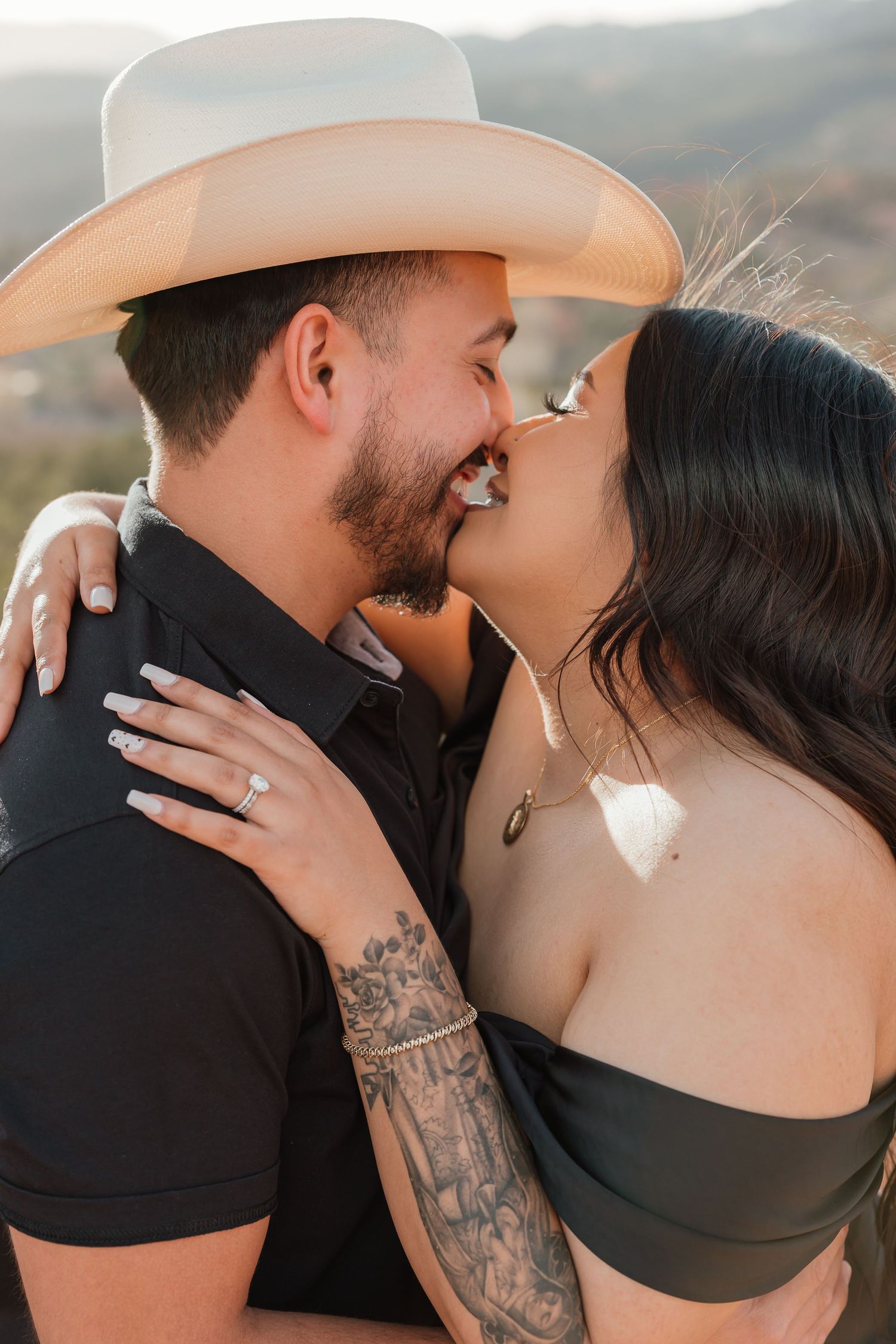 Romantic sequence of tender embrace and kiss between couple in western style clothing against scenic mountain backdrop.