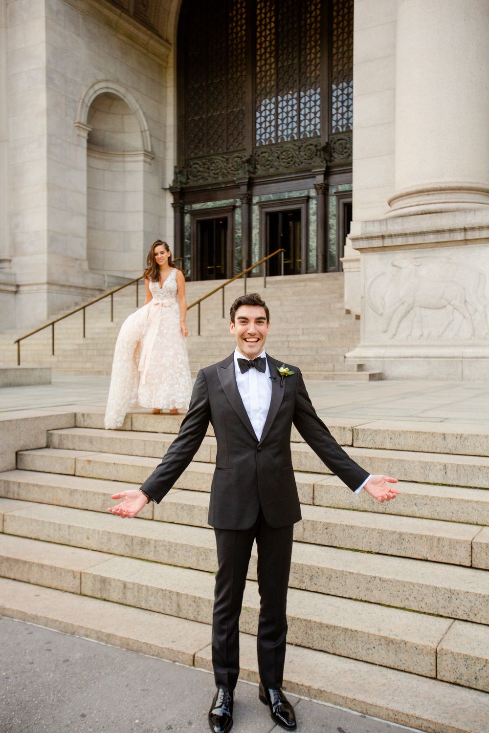 A formal wedding moment captured on grand stone steps with the bride in a blush gown and groom in classic tuxedo.