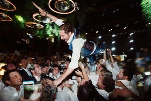 A crowd of concert goers dance and wave their hands excitedly in a dark nightclub atmosphere.