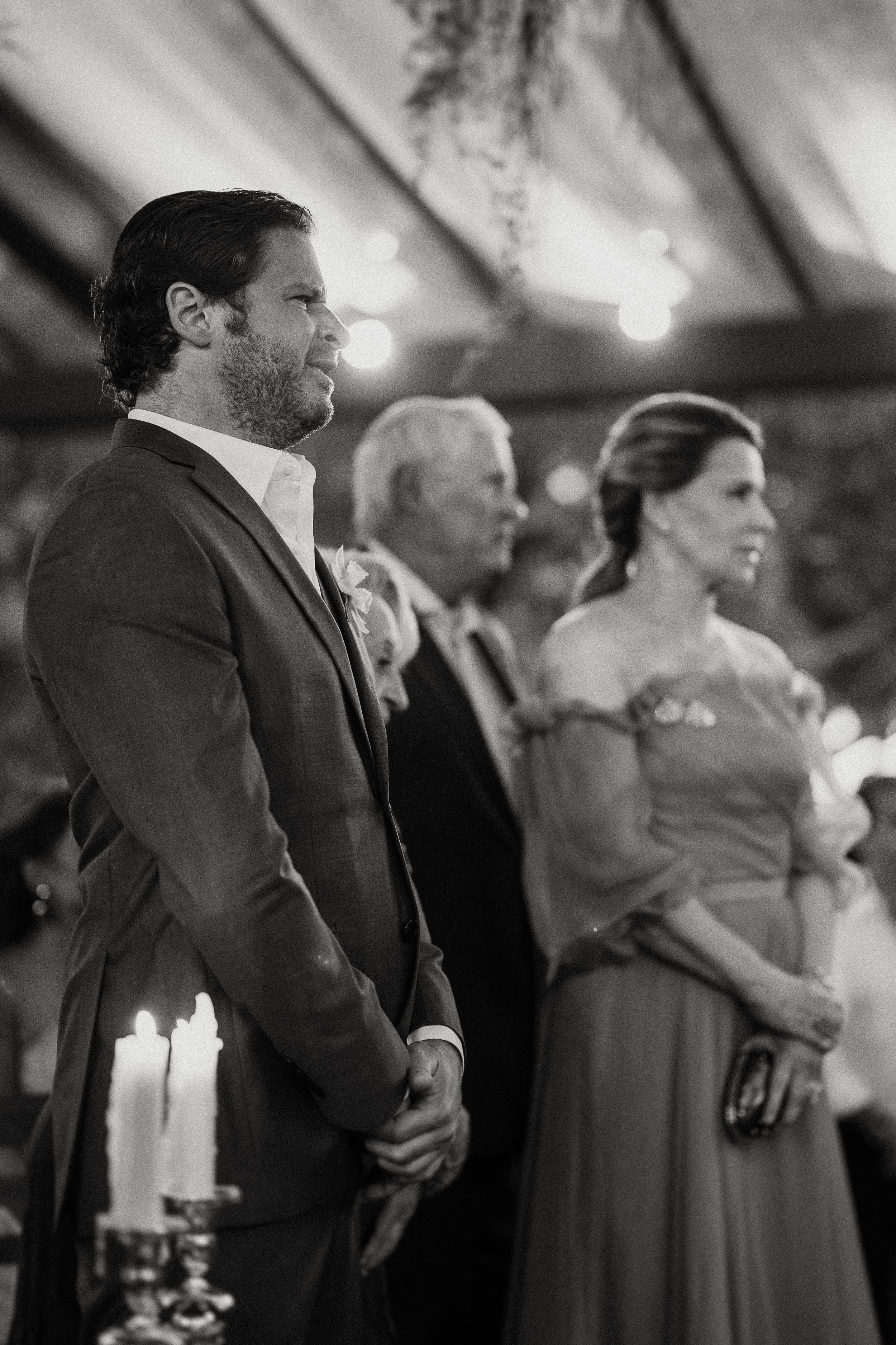 A black and white photograph showing attendees at a formal event standing solemnly in elegant attire.