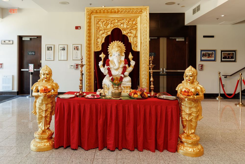 Golden statues and red tablecloths decorate an ornate cultural display in an indoor venue.