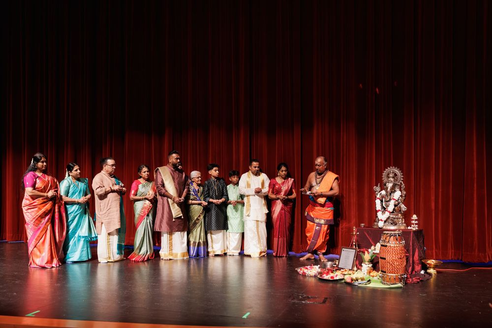 Group performance on stage with performers wearing colorful traditional Indian saris and costumes.
