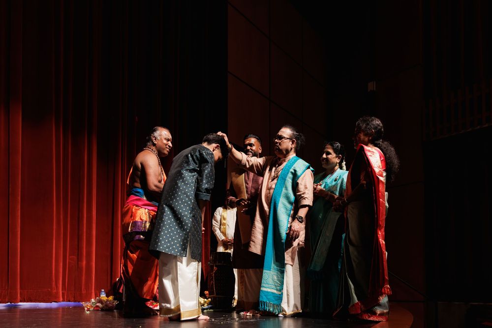 Cultural dance performance with cast members in vibrant traditional attire on theater stage.