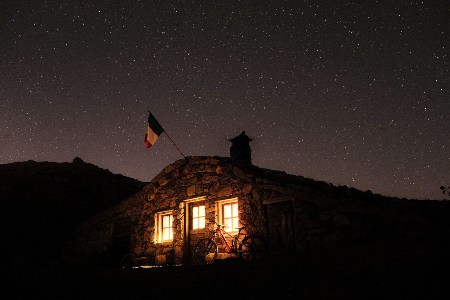 A series of nighttime photographs showing illuminated stone buildings against dark mountain and sky backdrops.