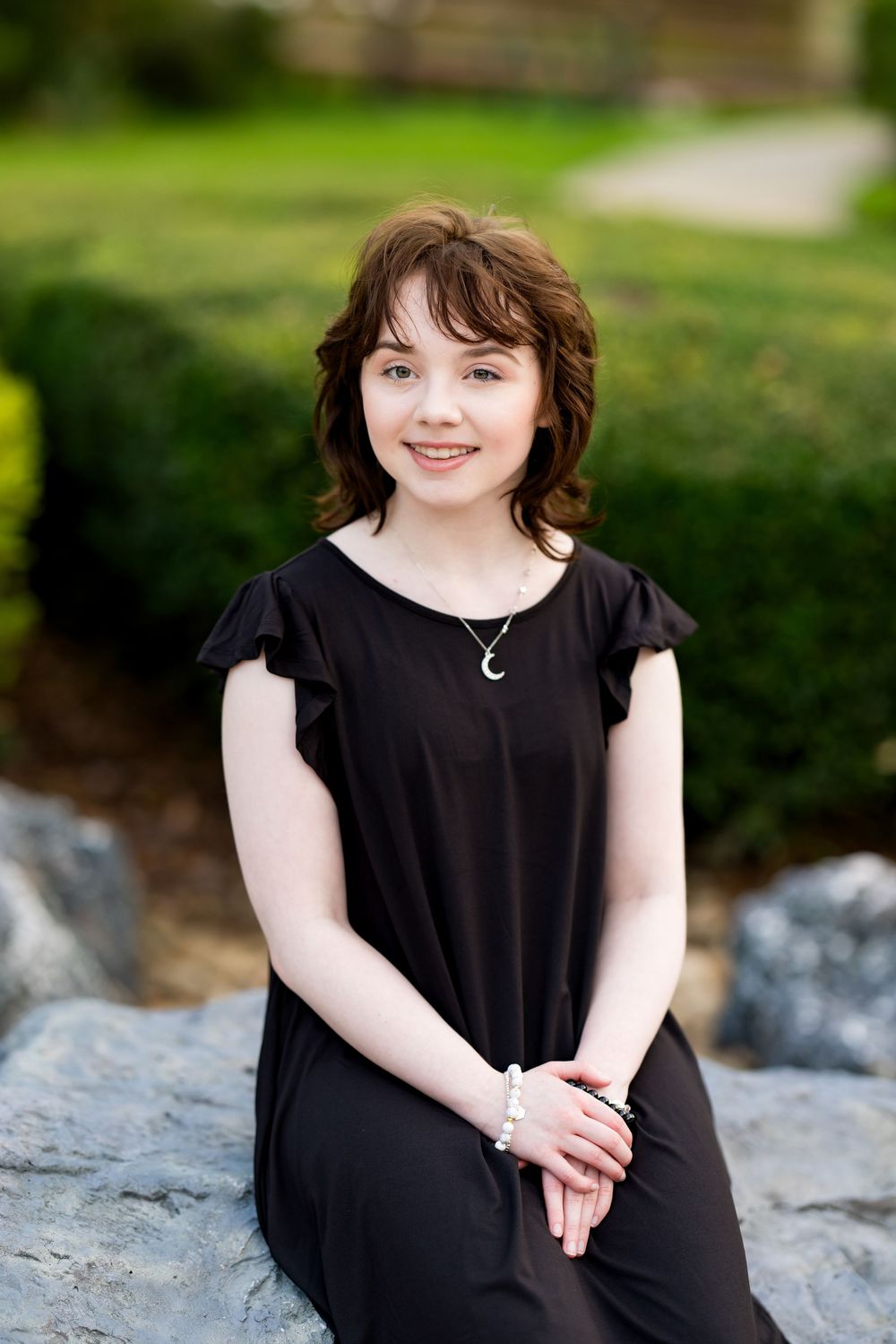 Portrait of someone seated on rock wearing black dress with natural background. Photos by Tampa Photographer DigitalMyst Photography