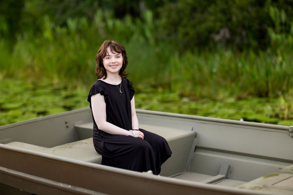 Person sitting in metal boat with green foliage in background. Photos by Tampa Photographer DigitalMyst Photography