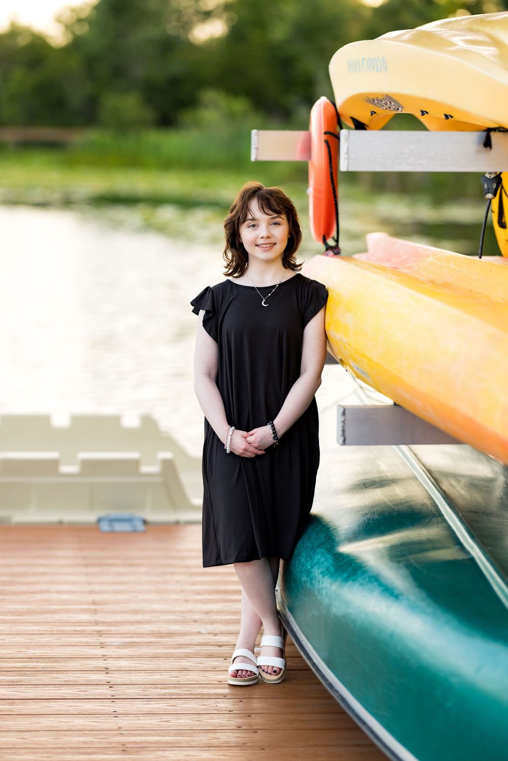 Person in black dress standing on dock next to stored yellow kayaks. Photos by Tampa Photographer DigitalMyst Photography