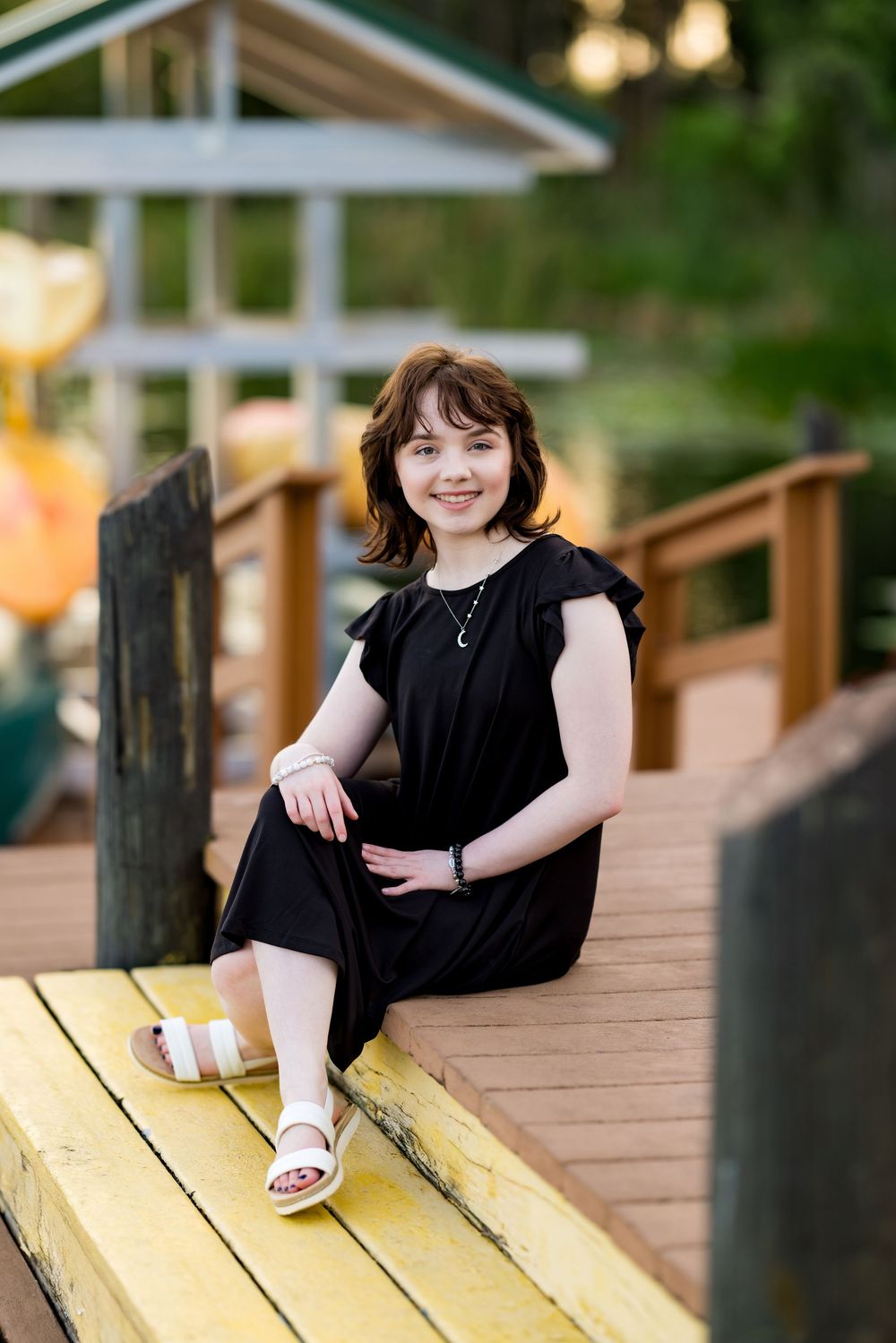 Person in black dress sitting on yellow bench at waterfront dock Land O Lakes FL. Photos by Tampa Photographer DigitalMyst Photography