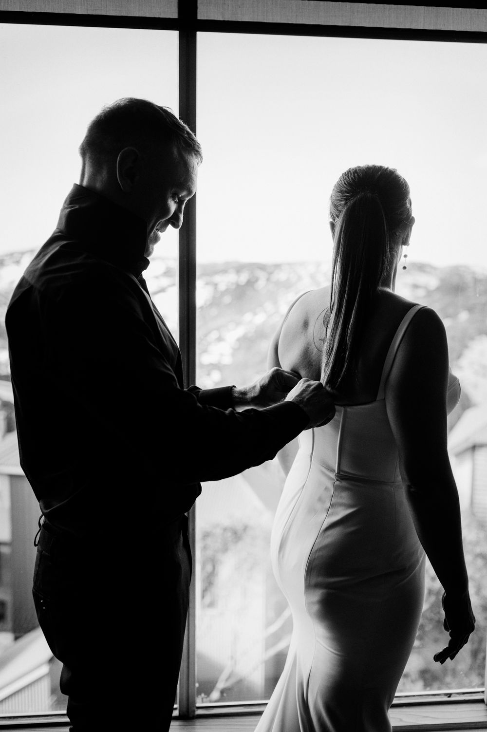 Silhouettes of people getting ready against bright windows with mountain views.
