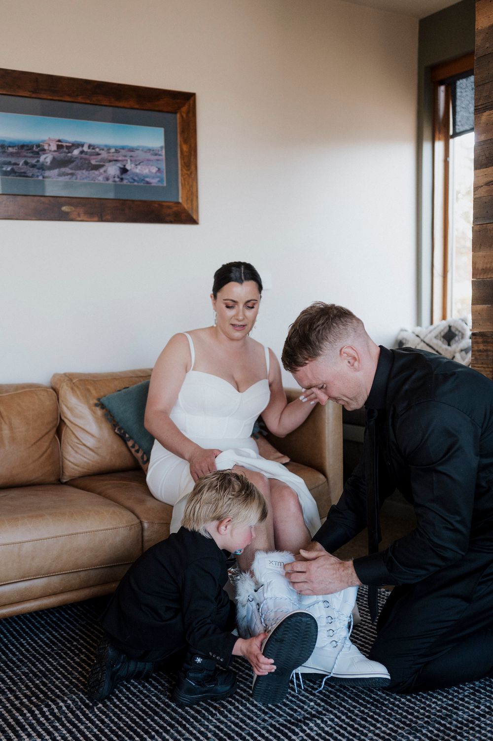 A couple in wedding attire sits together on a brown leather couch in sequence of intimate moments.