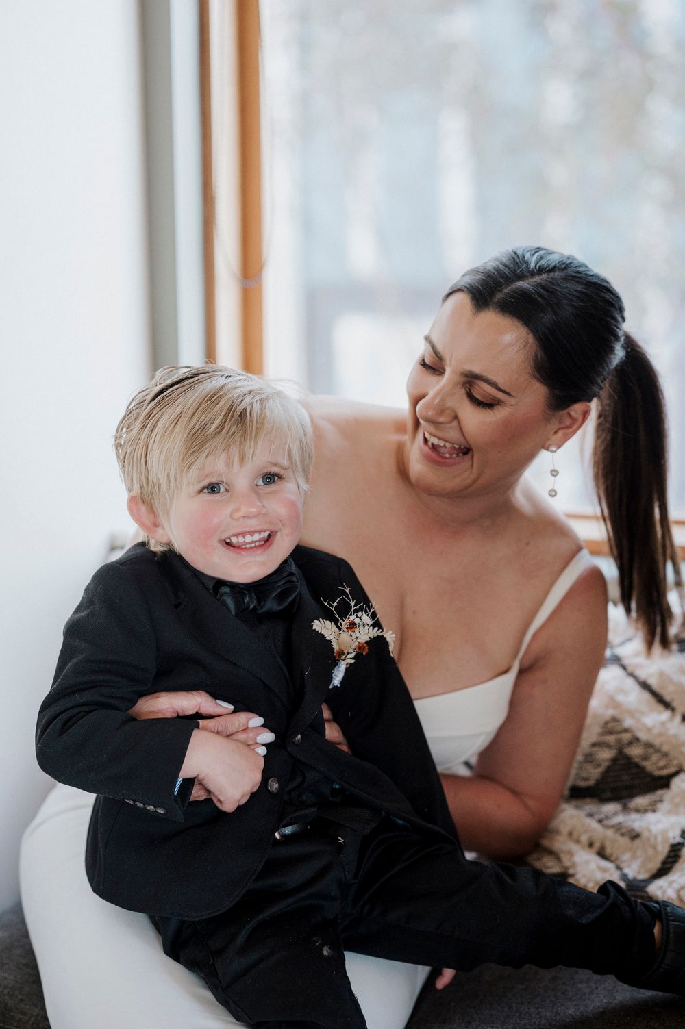 A joyful mother and young child share playful candid moments in a bright sunlit room.