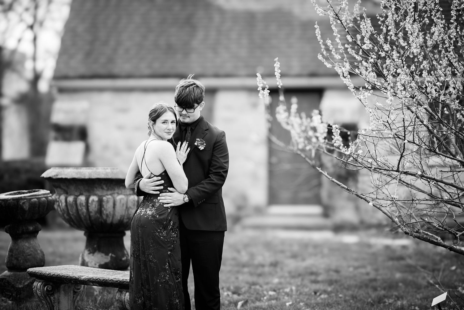 High school senior photographer Kansas City, a romantic black and white moment between two people embracing beside a decorative garden urn.