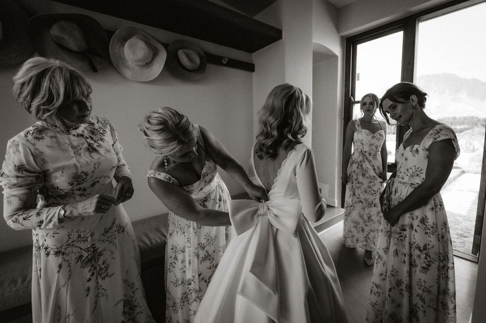 A black and white image shows bridesmaids in floral dresses helping with wedding preparations.