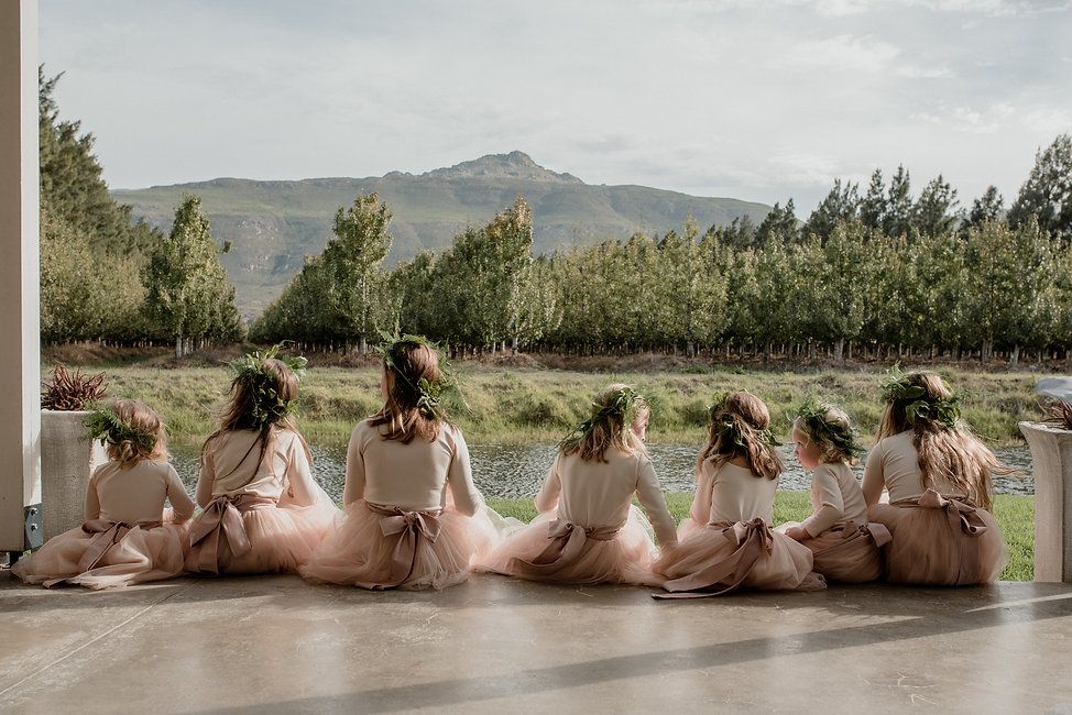 Bridesmaids in robes sitting in a row overlooking mountain landscape.