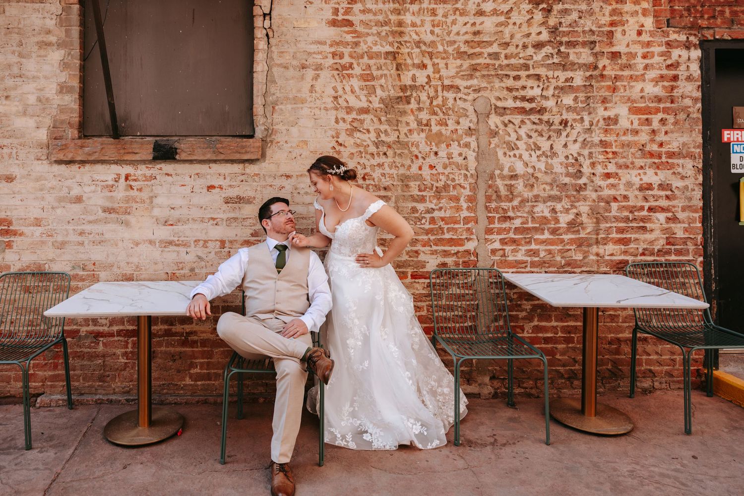 A collage of four wedding photos showing a couple lounging against a rustic brick wall in creative casual poses.