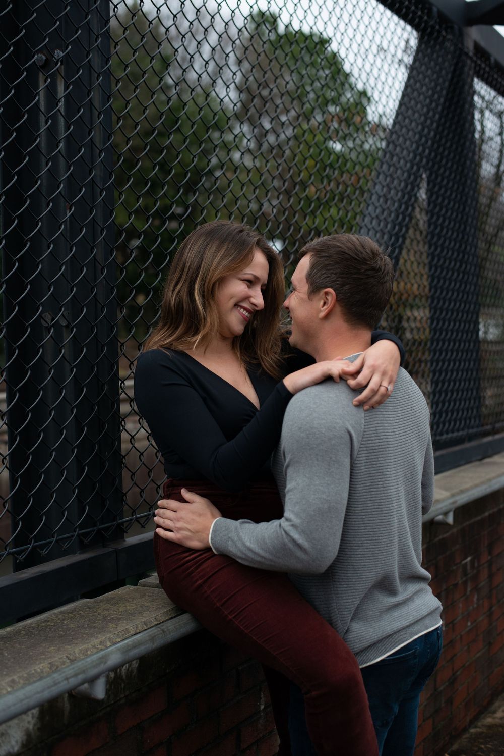 A couple shares an intimate moment against a chain link fence in a sequence of tender embraces.