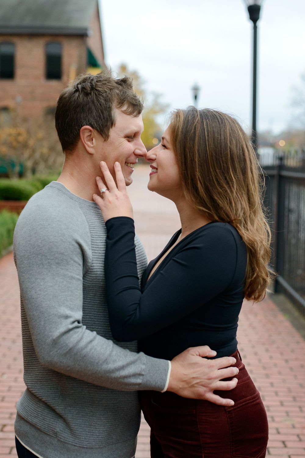 A romantic couple shares tender embraces and kisses along a brick pathway on an autumn day.