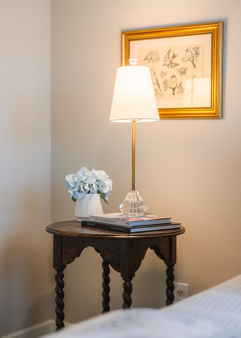 Classic side table with decorative turned legs displaying lamp and home accessories against a neutral wall.