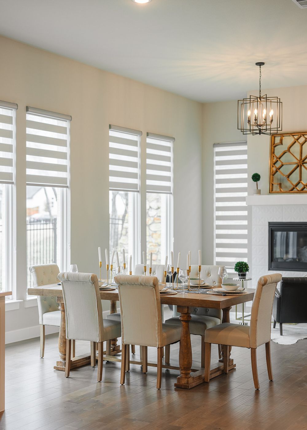 Modern open concept living room with white walls, wood floors and striped window shades features dining and seating areas.