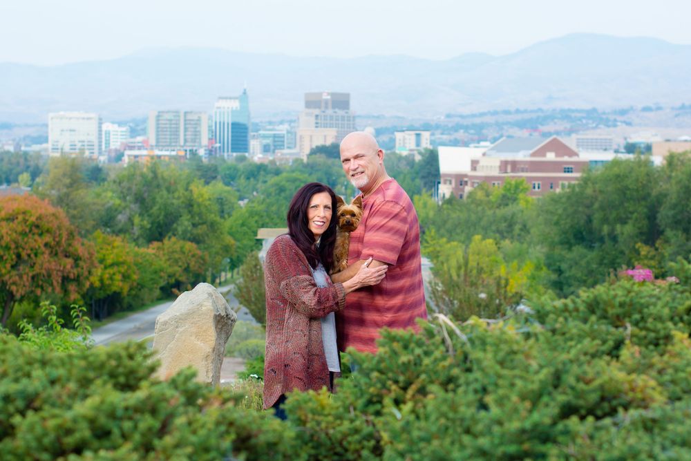 People enjoy an autumn day at a scenic overlook with city views and colorful fall foliage in the background.