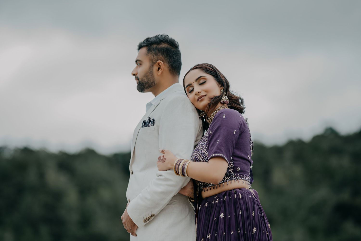 Couple embraces each other outdoors for intimate engagement photos in natural setting.