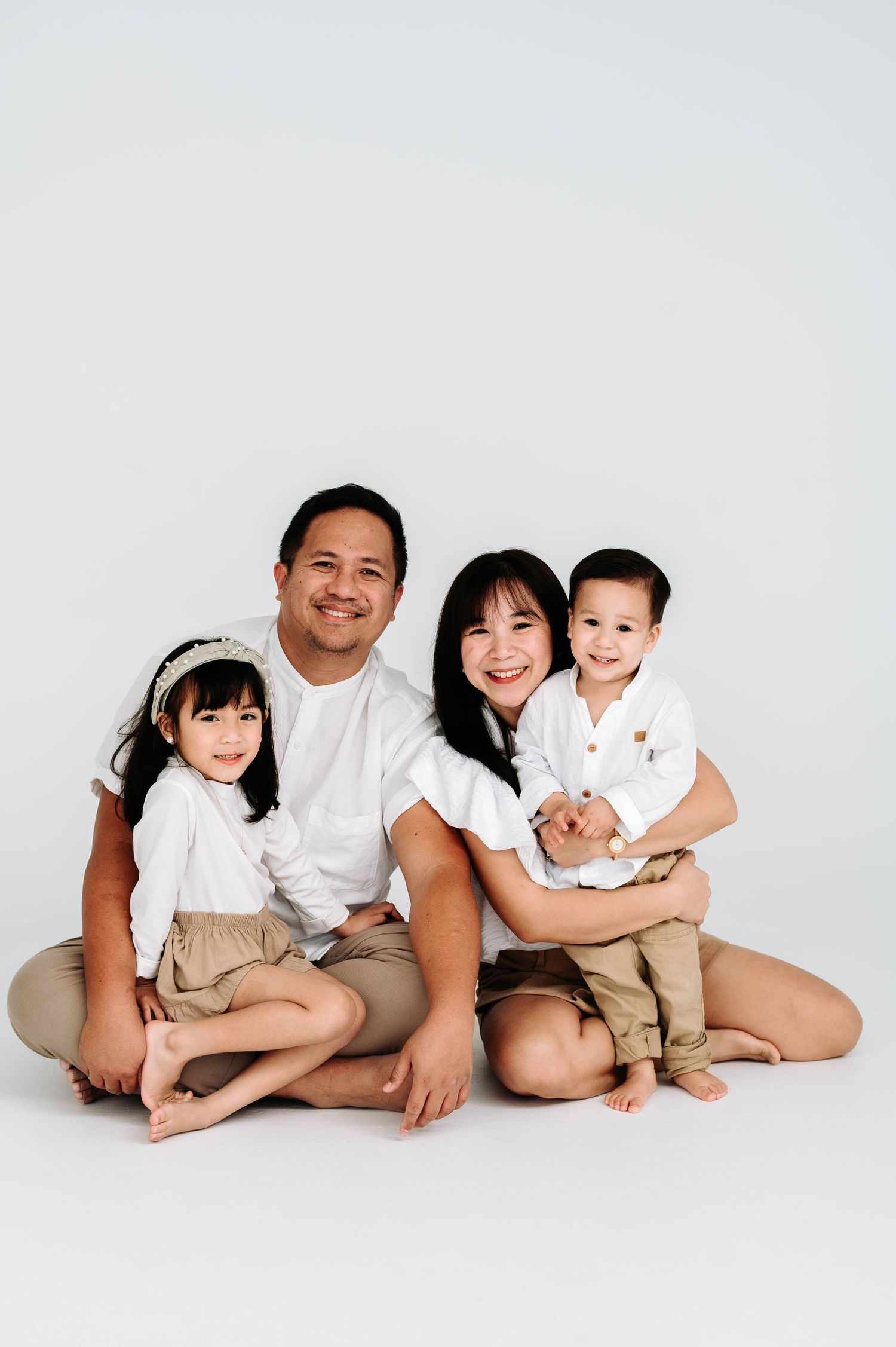 Family wearing white shirts and khaki shorts pose together on white background in progressive sequence.