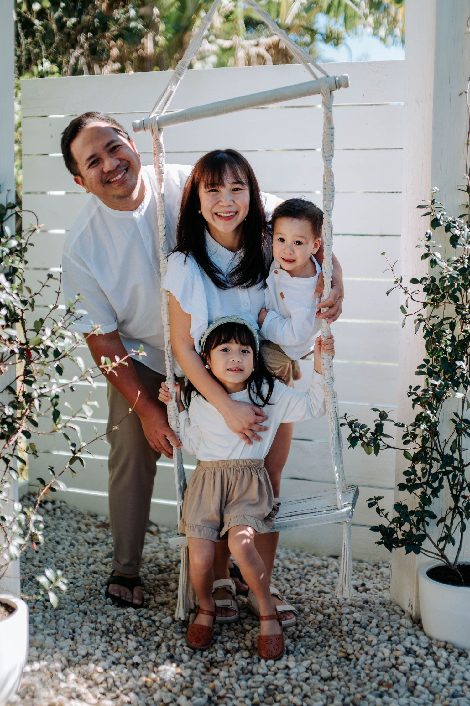 Outdoor family photo session with white fence and greenery background.