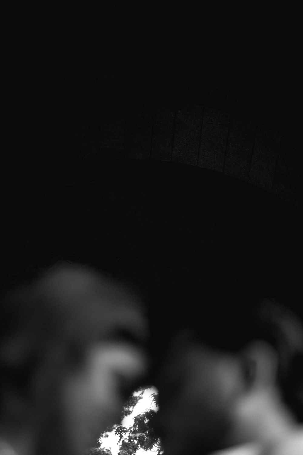 A bright flame burns against a dark background in this moody black and white photograph.