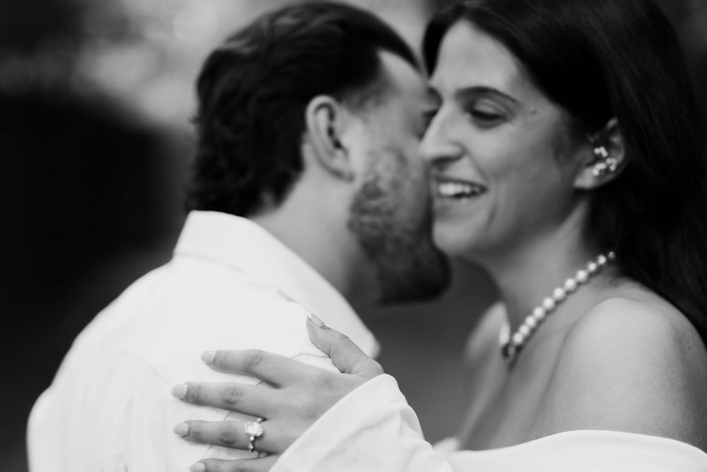 Black and white romantic wedding photo of a couple sharing a joyful moment together while embracing.