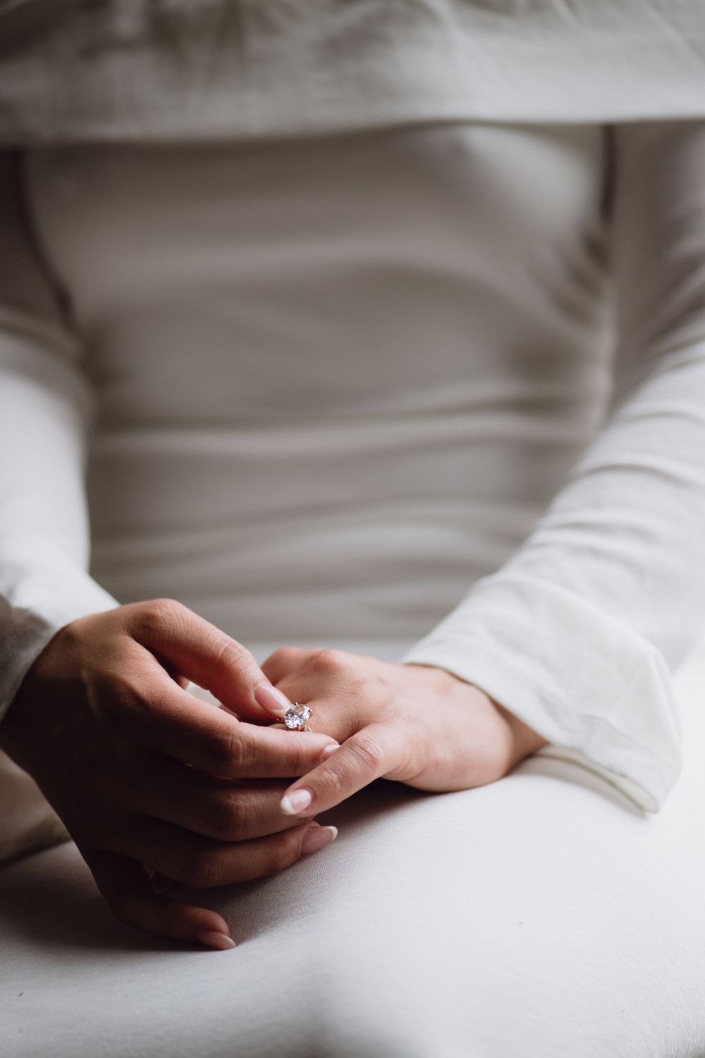 Soft white surface with hands gently resting in minimalist series showing tranquil peaceful positions on white background.