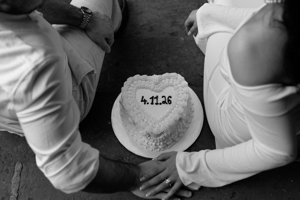 A black and white photograph shows a simple frosted cake with a numeric date visible on its surface.