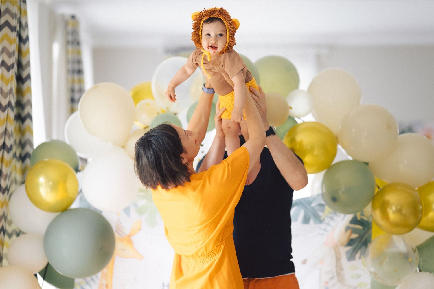 A group of people throwing confetti and celebrating with balloons in a bright room filled with festive decorations.