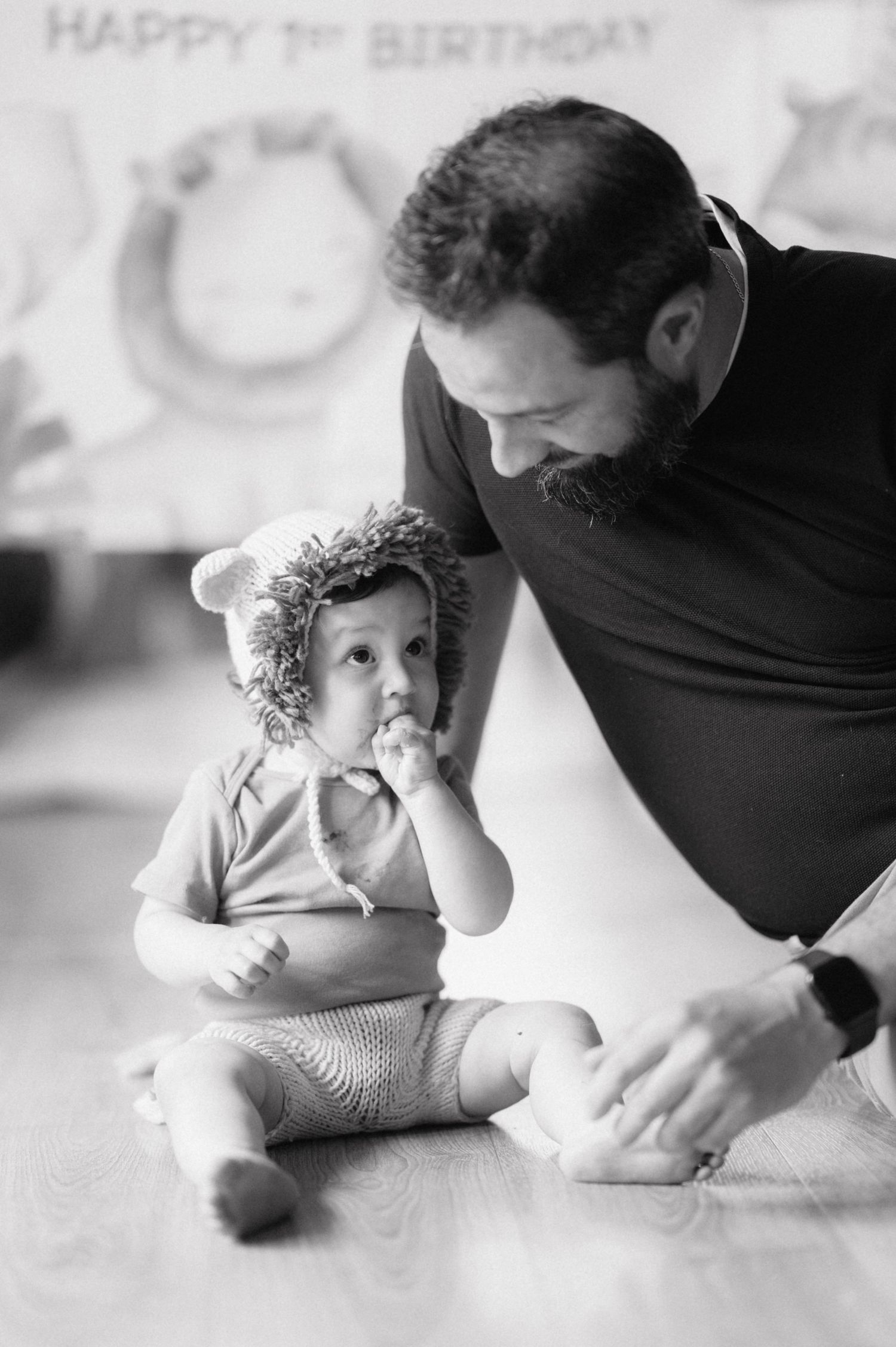 Black and white portrait series showing tender interaction between parent and baby during first birthday photoshoot.