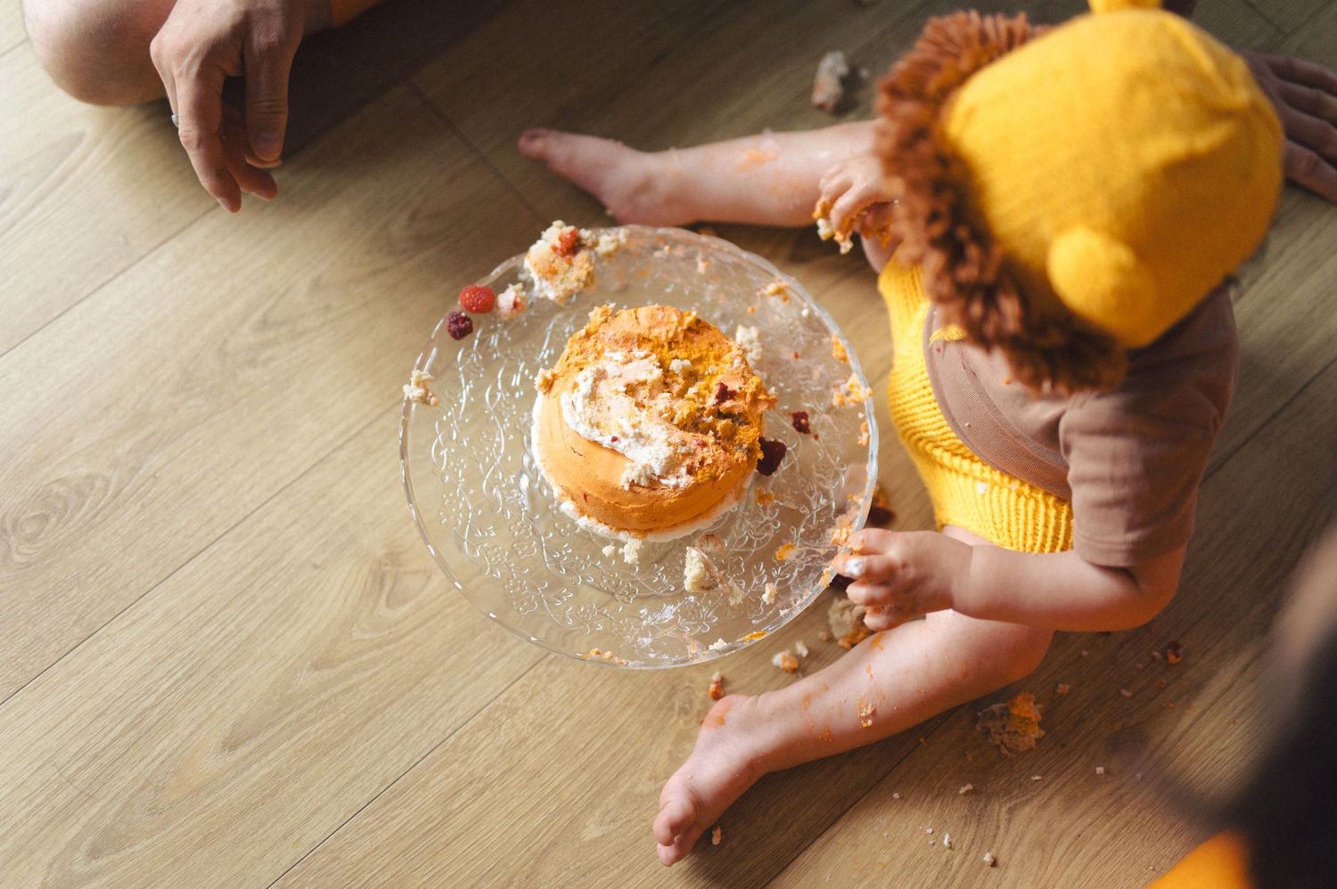 Hands squeezing fresh orange juice using a glass citrus juicer on wooden table.
