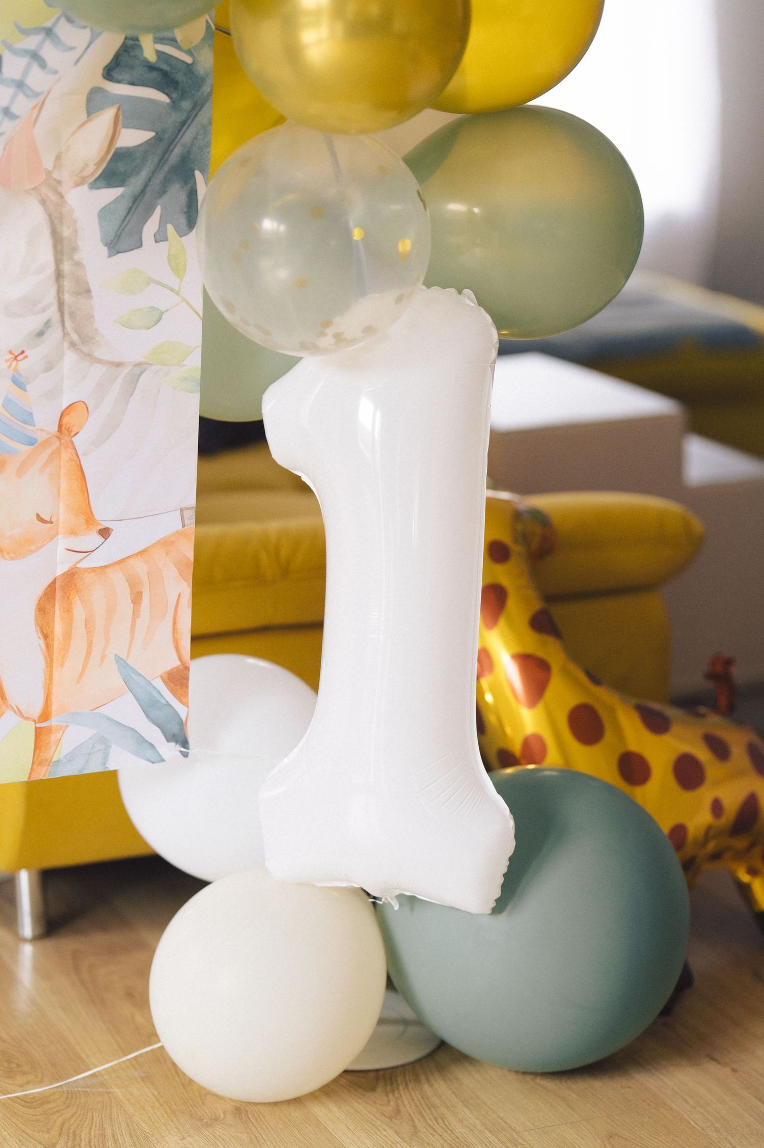 First birthday party decorations with number one balloon, colorful balloons, and a stuffed giraffe toy on display.