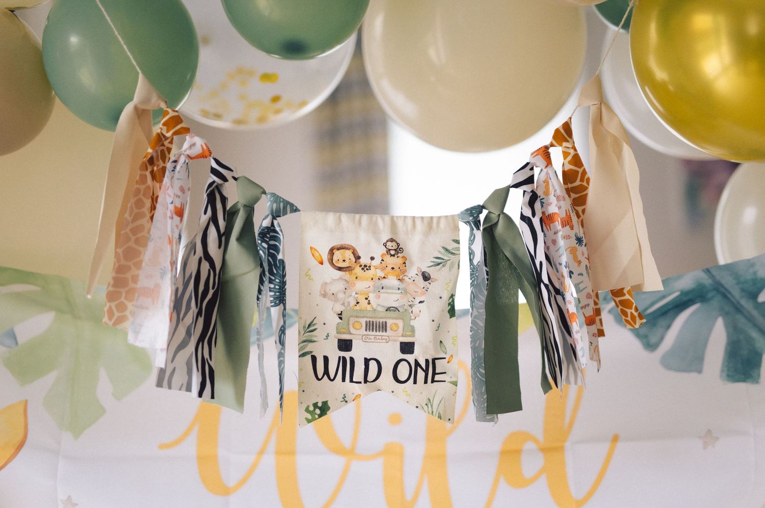 Festive party decorations featuring blue and gold balloons with a 'Wild One' banner hanging above.