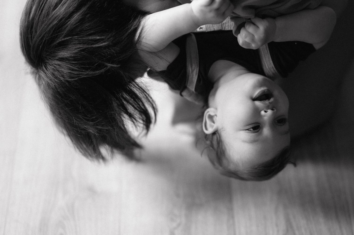 Black and white artistic portrait shows two people lying down with long dark hair in dramatic overhead composition.