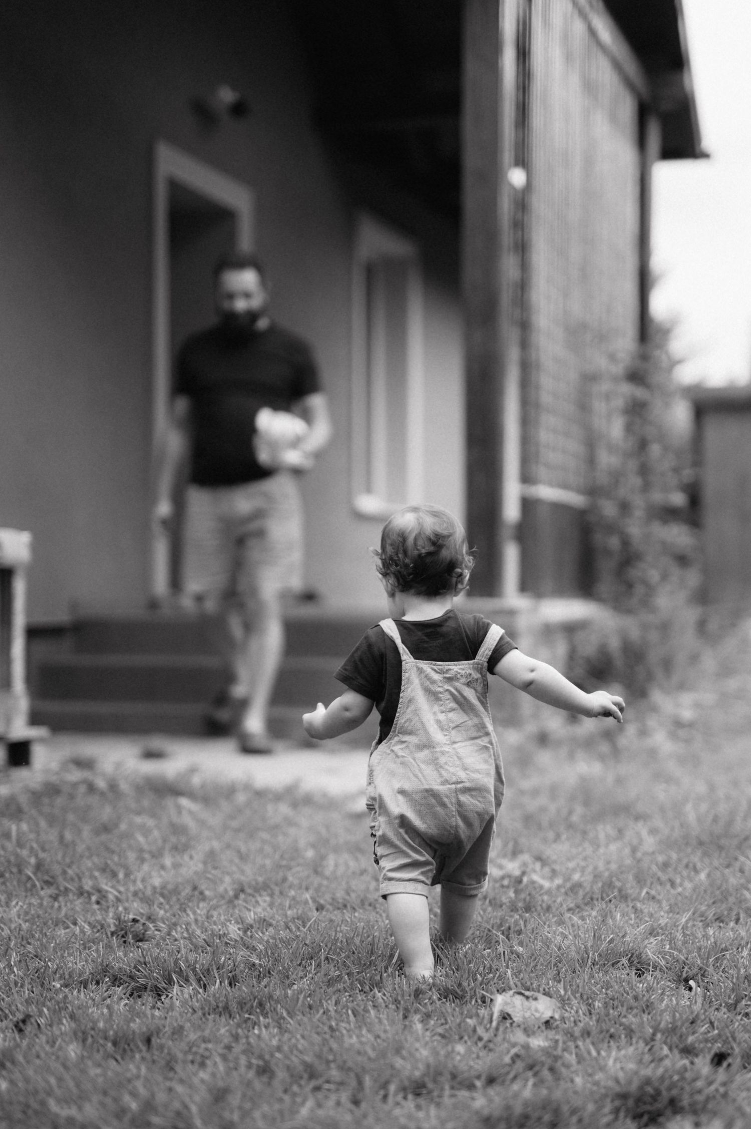 A child running and playing on a grassy slope shown in four sequential black and white photographs.
