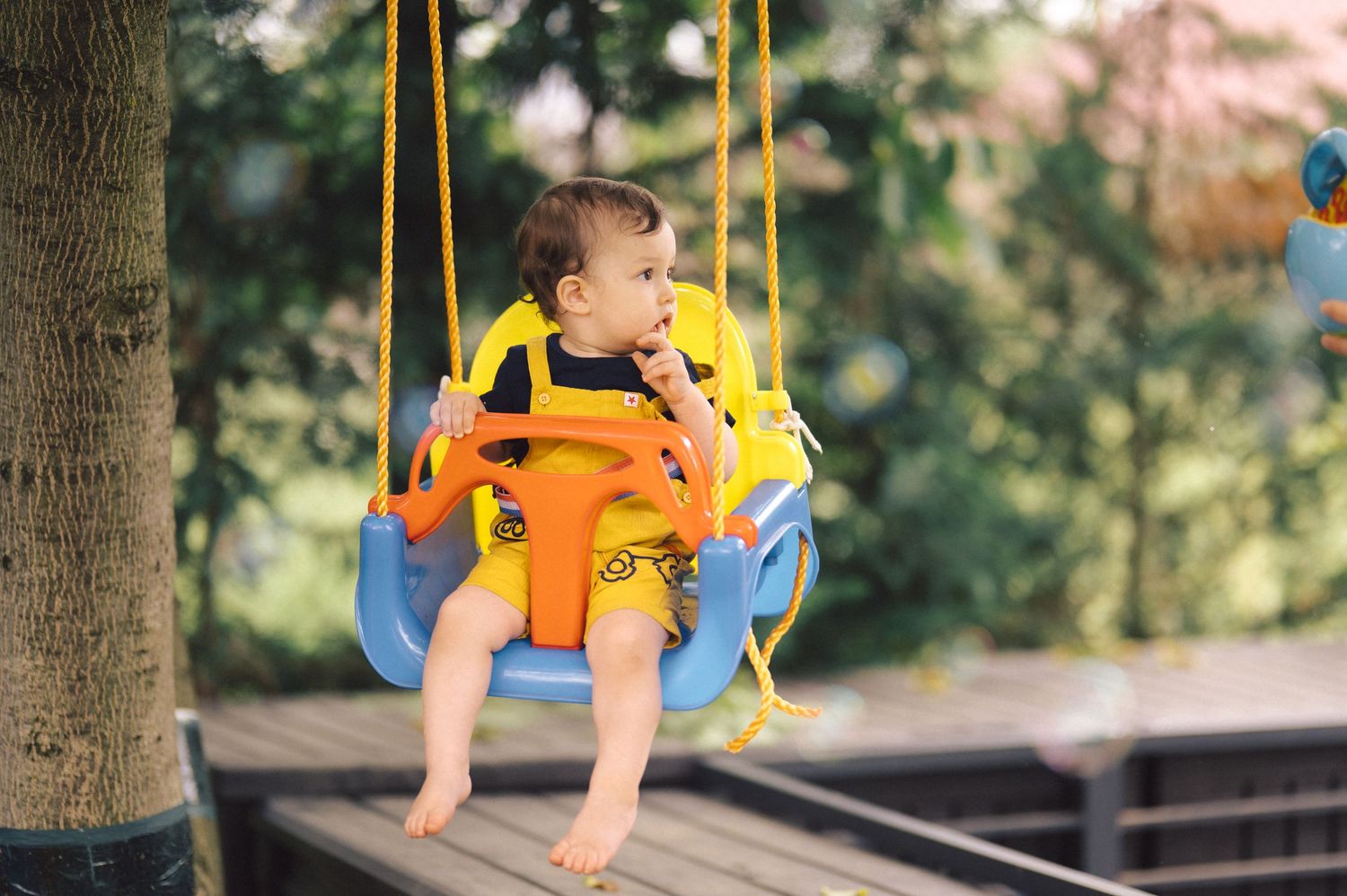 Child enjoys swinging on a yellow playground swing set on a bright sunny day.